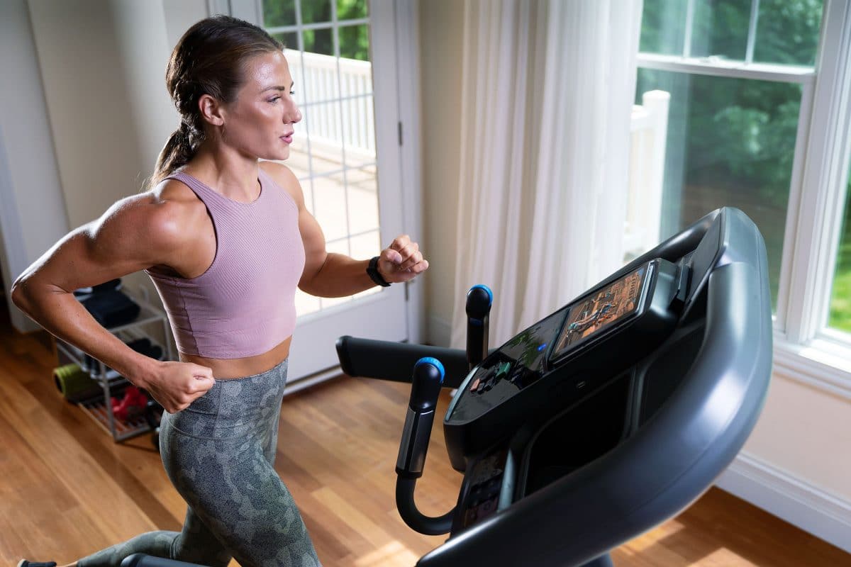 A woman is running on a treadmill in her home.