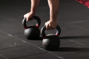 man lifting kettle bells - Fitness Expo