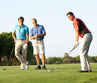 Three men playing golf on a golf course.