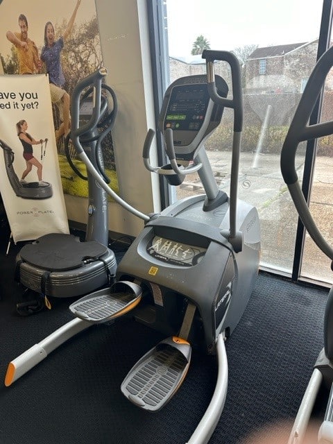 A gym with a cardio machine and a sign