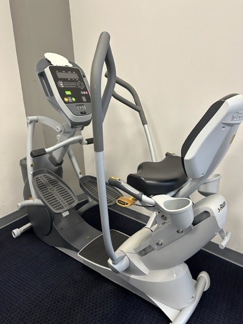 Elliptical machine with seat and handlebars in a room.