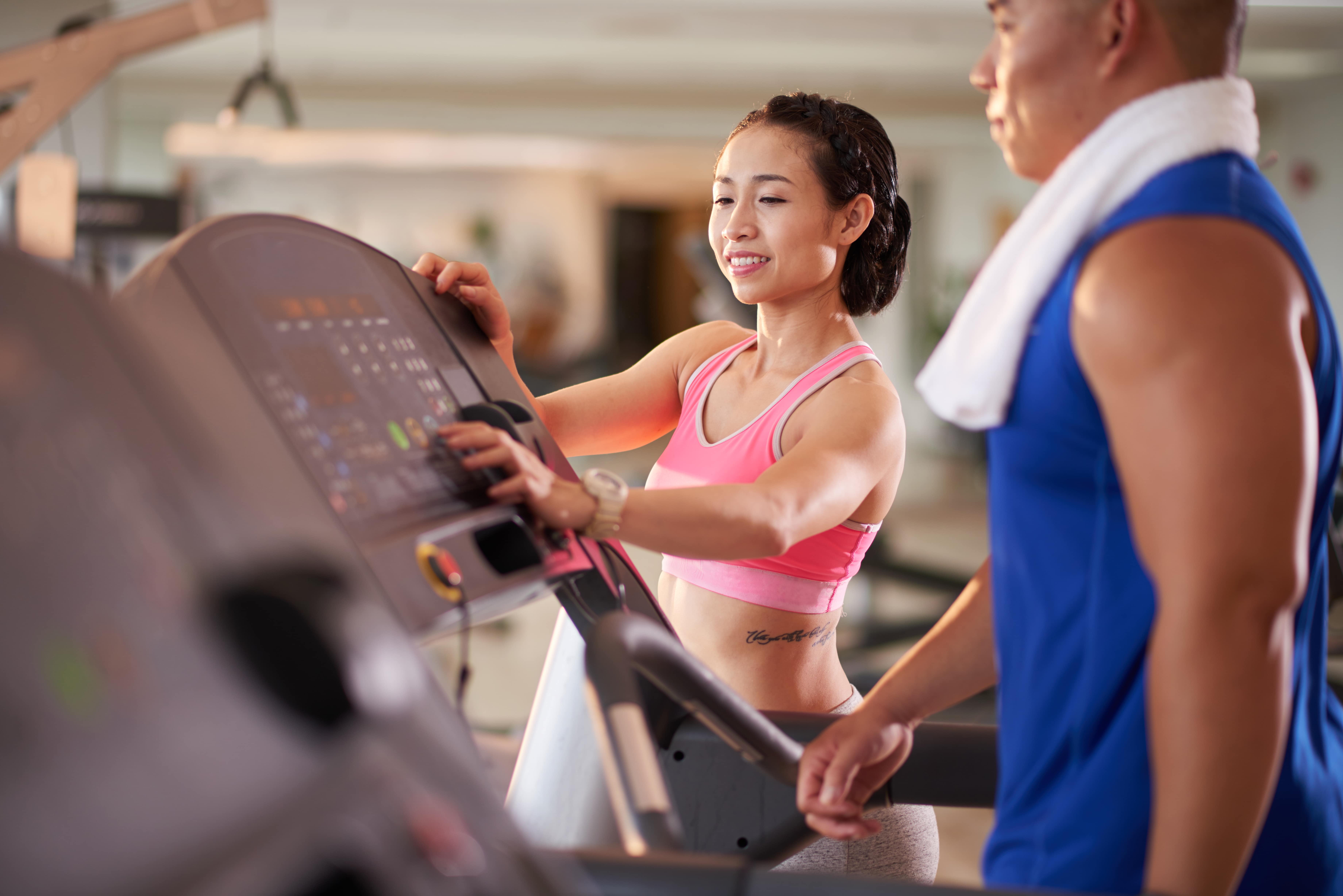 woman helping other with treadmill